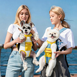 Two women outdoors carrying dogs in DONOYOYO pet carrier backpacks — a Schnauzer in yellow/white and a Pomeranian in blue denim/yellow — showing front-facing carry style by the waterfront
