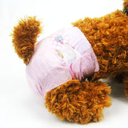 Close-up rear view of brown Toy Poodle wearing Dono disposable female dog diaper in pink cartoon print, showing diaper fit around hindquarters with elastic leg openings, on white background